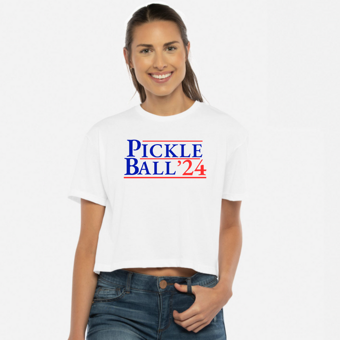 Introducing our EXCLUSIVE “PickleBall ‘24” Women’s Cropped Tee – because who says politics can’t be a dill-lightful game?  Embrace the ultimate combo of PickleBall ‘24 and the upcoming 2024 Election!! Wear it all proudly and let everyone know you’re on #TeamPickle. PickleBall ‘24 is the pickle-fied fashion statement that’s both baller and bipartisan!  *Pickleball ’24 is also available in tanks, hoodies, sweatshirts & trucker hats- for guys and gals!! 