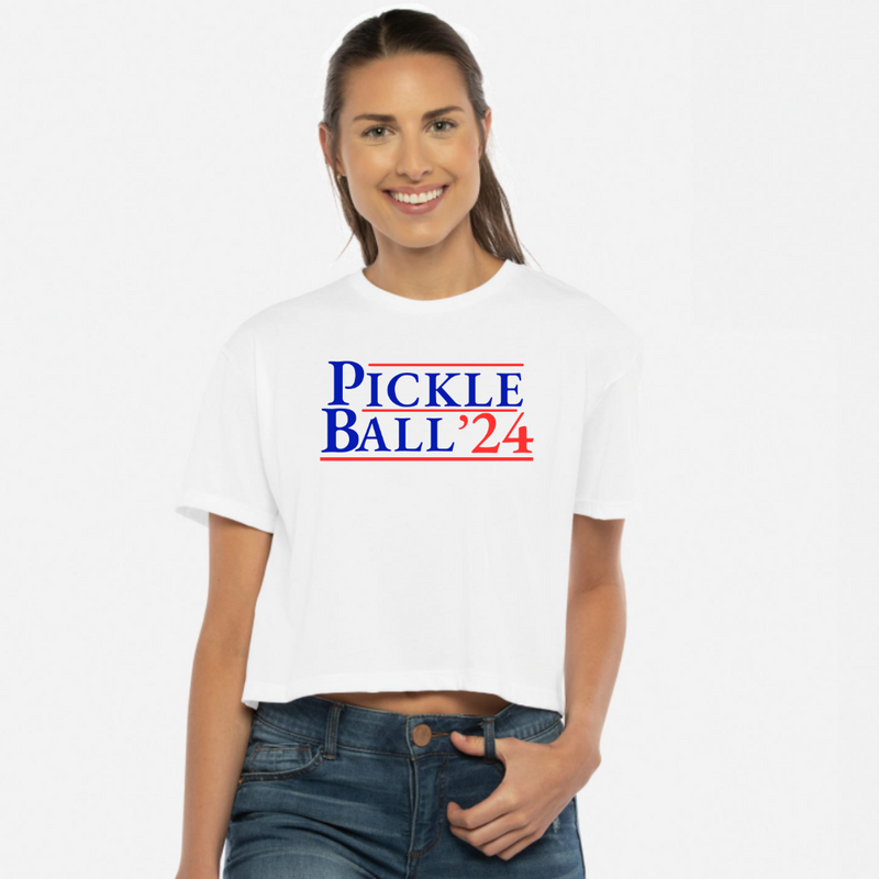 Introducing our EXCLUSIVE “PickleBall ‘24” Women’s Cropped Tee – because who says politics can’t be a dill-lightful game?  Embrace the ultimate combo of PickleBall ‘24 and the upcoming 2024 Election!! Wear it all proudly and let everyone know you’re on #TeamPickle. PickleBall ‘24 is the pickle-fied fashion statement that’s both baller and bipartisan!  *Pickleball ’24 is also available in tanks, hoodies, sweatshirts & trucker hats- for guys and gals!! 